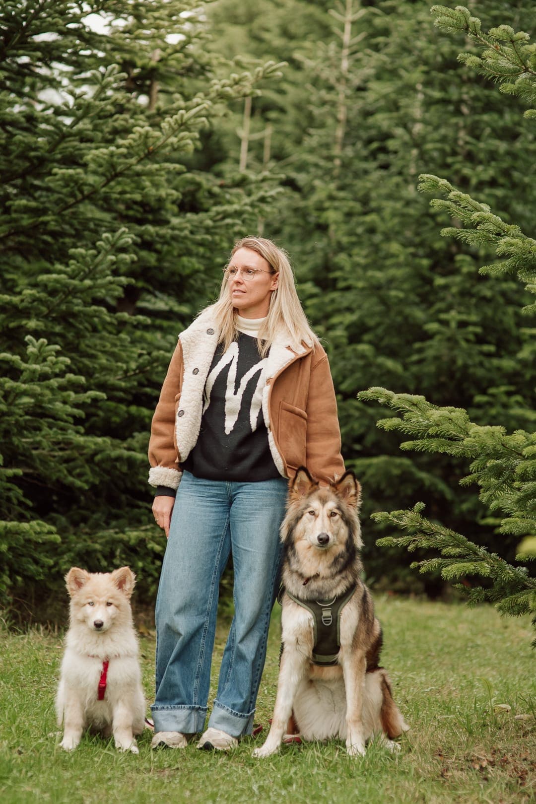 Stéphanie staat in het gras met haar twee wolfhonden naast zich